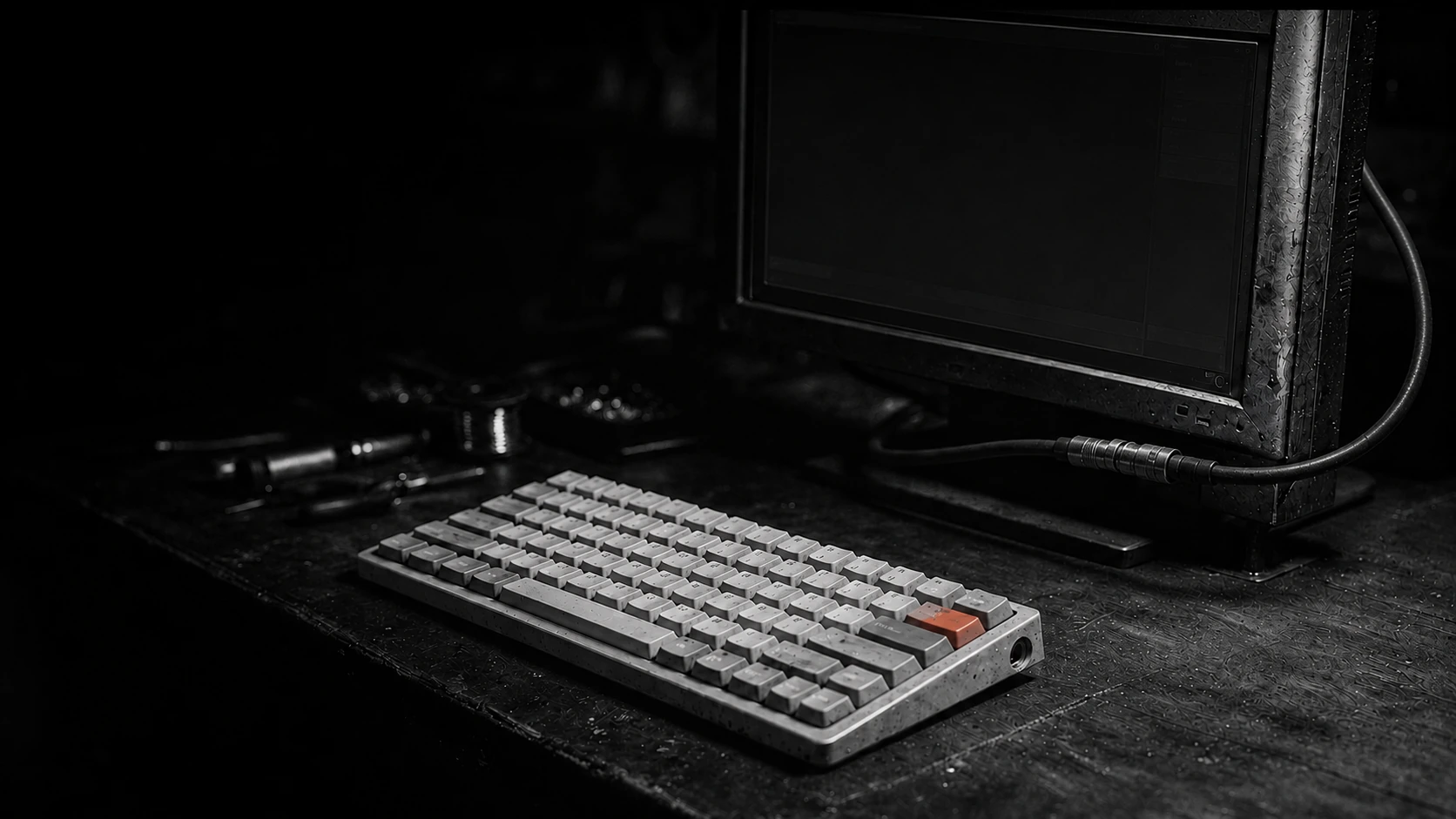 An industrial workbench with a dormant monitor and one red keyboard key
