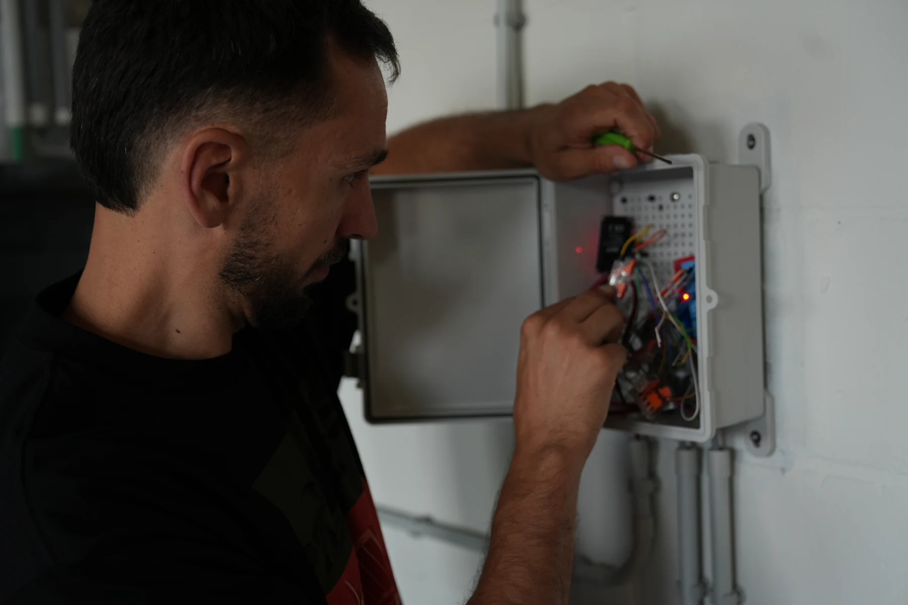 Mehdi wiring the electronics inside a wall-mounted control cabinet
